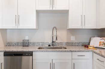 A kitchen with white cabinets and a granite countertop.